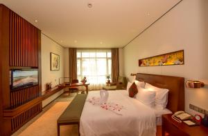 a hotel room with a bed and a television at Wuxi Yew Resort in Wuxi