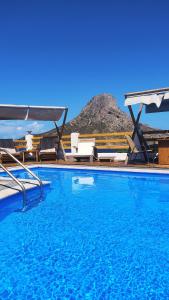 a swimming pool with chairs and a mountain in the background at Fatolitis Studios in Masouri
