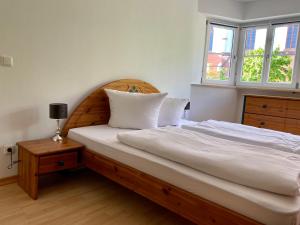 a bedroom with a bed with a wooden headboard and two windows at 3 Zimmer Ferienwohnung Hellmairs in Landsberg am Lech