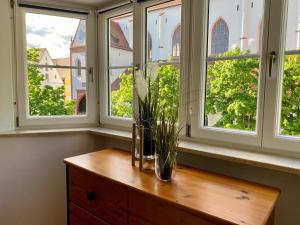 un jarrón en una mesa de madera frente a las ventanas en 3 Zimmer Ferienwohnung Hellmairs en Landsberg am Lech