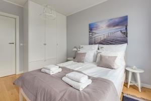 sypialnia z dużym białym łóżkiem z ręcznikami w obiekcie Downtown Apartments Navio by the Sea w Gdańsku