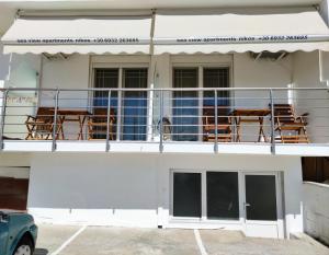 a balcony with tables and chairs on a building at Sea View Apartments Nikos in Nea Peramos