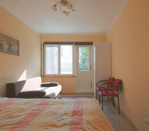 een slaapkamer met een bed, een stoel en een raam bij Apartamentai Juodkrantėje in Juodkrantė