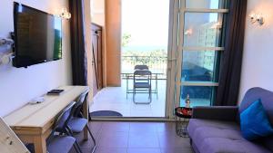 a living room with a couch and a tv and a balcony at Appartement 174, Vue mer à Cap Esterel By Palmazur in Saint-Raphaël