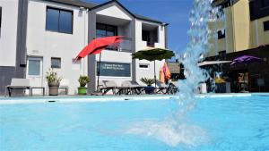uma piscina com um guarda-sol vermelho e uma fonte em Le Thalassa Hôtel & Spa em Camaret-sur-Mer