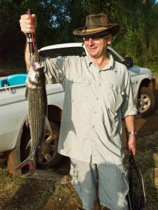 Un uomo con un cappello che tiene un pesce di Needles Lodge a Marloth Park