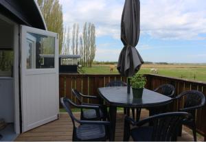 eine Terrasse mit einem Tisch, Stühlen und einem Sonnenschirm in der Unterkunft Pipowagen Vlinder bij Pipowagen & Kampeerhoeve s Gravenhof in Netterden