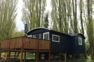ein schwarzes winziges Haus auf einem Holzstand in einem Wald in der Unterkunft Pipowagen Vlinder bij Pipowagen & Kampeerhoeve s Gravenhof in Netterden