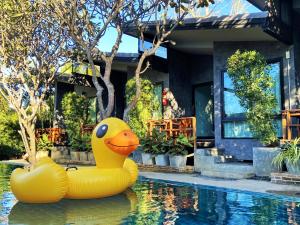 two rubber ducks sitting in the water in front of a house at Family House Zen Boutique Resort in Pai