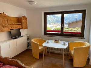 Appartments-Hutter في نيوكيرشين آم غروسفينديغر: غرفة معيشة مع طاولة وكراسي ونافذة