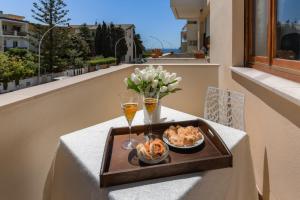 taca z jedzeniem i napojami na stole na balkonie w obiekcie Magnolia - Dario apartment w mieście Fertilia