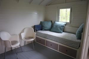een kleine slaapkamer met een bed en 2 stoelen bij Pipowagen Vlinder bij Pipowagen & Kampeerhoeve s Gravenhof in Netterden