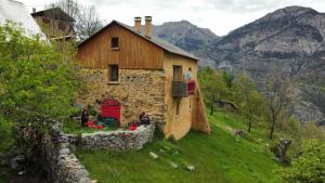 a house on a hill with people sitting outside of it at Le Seuil De Mes Reves in Le Lauzet-Ubaye