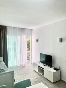 ein weißes Wohnzimmer mit einem TV und einem Sofa in der Unterkunft Alisios Dream in Corralejo