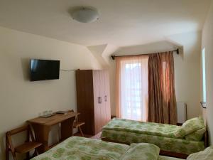 a hotel room with two beds and a desk at Casa Zmeilor in Tăşnad