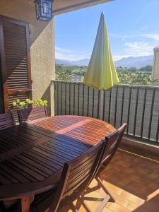 een houten tafel en stoelen op een balkon met een parasol bij Les logis de l'aqueduc in Ajaccio