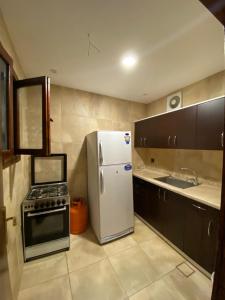 a kitchen with a white refrigerator and a stove at Sadeem Village & Chalet in Al Shafa