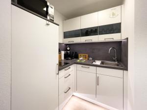 a kitchen with white cabinets and a sink at FeWo Längl -Alpenguck- mit Pool und Sauna im Allgäu in Scheidegg