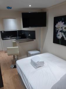- une chambre avec un lit blanc et une télévision à écran plat dans l'établissement Budget Ensuite Room in Thamesmead, à Londres