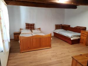 two beds in a room with wooden floors at Letti Vendégház in Kővágóörs