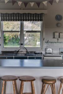 a kitchen with a counter and stools in front of a sink at Polperro, a quintessential seaside experience in Robe