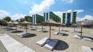 MUR Apartament Alezzi Beach Resort في مامايا نورد نافورداي: شاطئ به العديد من مظلات القش وكراسي الصالة