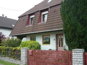 a house with a red fence in front of it at Füvesi Vendégház in Balatonfüred