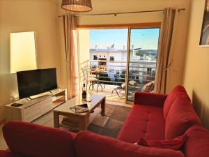 a living room with a red couch and a television at Modern Ocean, Garden & Pool view Condo by BeCherish in Albufeira
