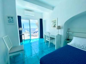 a bedroom with a bed and a desk with a view of the ocean at Hotel Casa Sofia in Ischia