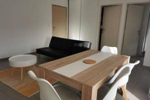 sala de estar con mesa de madera y sillas blancas en Appartement T2 accessible PMR avec terrasse et garage, en Onet le Château