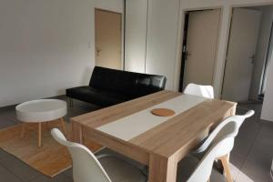 - un salon avec une table en bois et des chaises blanches dans l'établissement Appartement T2 accessible PMR avec terrasse et garage, à Onet le Château