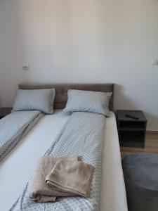 Una cama con dos almohadas y una bolsa. en CASA BIA CRIBO Sannicolau de Munte - bai termale en Săcueni