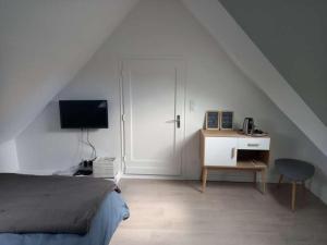 een slaapkamer met een bed en een bureau met een televisie bij Havre de paix et jardin tropical. Chambre privée in Le Rheu