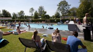 a group of people sitting in chairs by a swimming pool at Holiday rentals in Velsen-Zuid