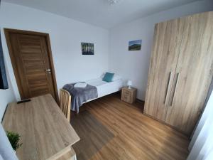 a small bedroom with a bed and a wooden door at Willa Biały Domek in Ustroń