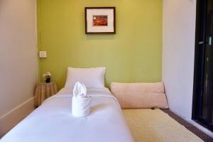 a bedroom with a white bed and a green wall at พี่ดา เฮ้าส์ (P'Da House) in Hat Yai