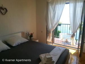a bedroom with a bed with a view of a balcony at Kvarner Apartments - Mošćenička Draga in Mošćenička Draga