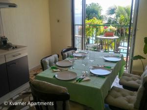 a dining room table with a green tablecloth and chairs at Kvarner Apartments - Mošćenička Draga in Mošćenička Draga