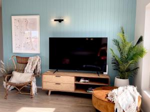 a living room with a flat screen tv on a wooden entertainment center at Seabreeze at Semaphore #8 - On the Esplanade in Semaphore