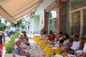 a group of people sitting at tables at a restaurant at Hotel Madrid in Cattolica