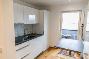 eine Küche mit weißen Schränken, einem Waschbecken und einem Fenster in der Unterkunft Bodenseedomizil in Lochau