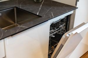 an open dishwasher in a kitchen with a black counter top at Bodenseedomizil in Lochau