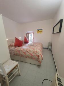 a bedroom with a bed with red pillows and a chair at Monolocale caterina in Corniglia