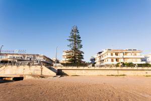 a bridge over a beach with buildings and a tree at Case Madira in Marina di Ragusa