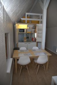 eine kleine Küche mit einem Holztisch und weißen Stühlen in der Unterkunft Gîte alsacien in Eckwersheim
