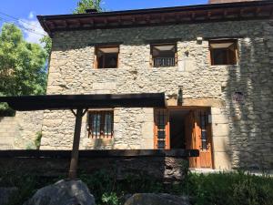 una antigua casa de piedra con puerta de madera en Casa Rural La Casita del Río, en Villarcayo