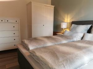 1 dormitorio con 1 cama con cómoda y armario blanco en Ferienwohnung am See, en Haidmühle