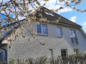 een grijs bakstenen huis met witte ramen en een boom bij Wormshöft 16 in Hasselberg