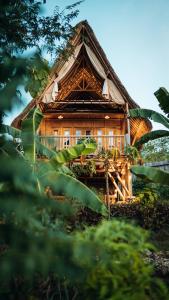 a large wooden house with a thatched roof at Penida Bambu Green Suites in Nusa Penida