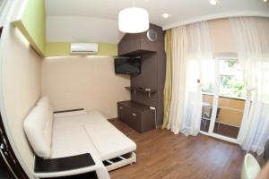 ein kleines Zimmer mit einem weißen Sofa und einem TV in der Unterkunft Apartments on Abrikosovaya in Odessa